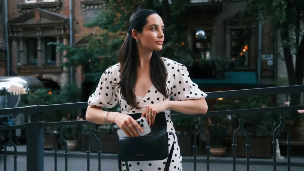 Sac à main noir porté avec une robe blanche à pois